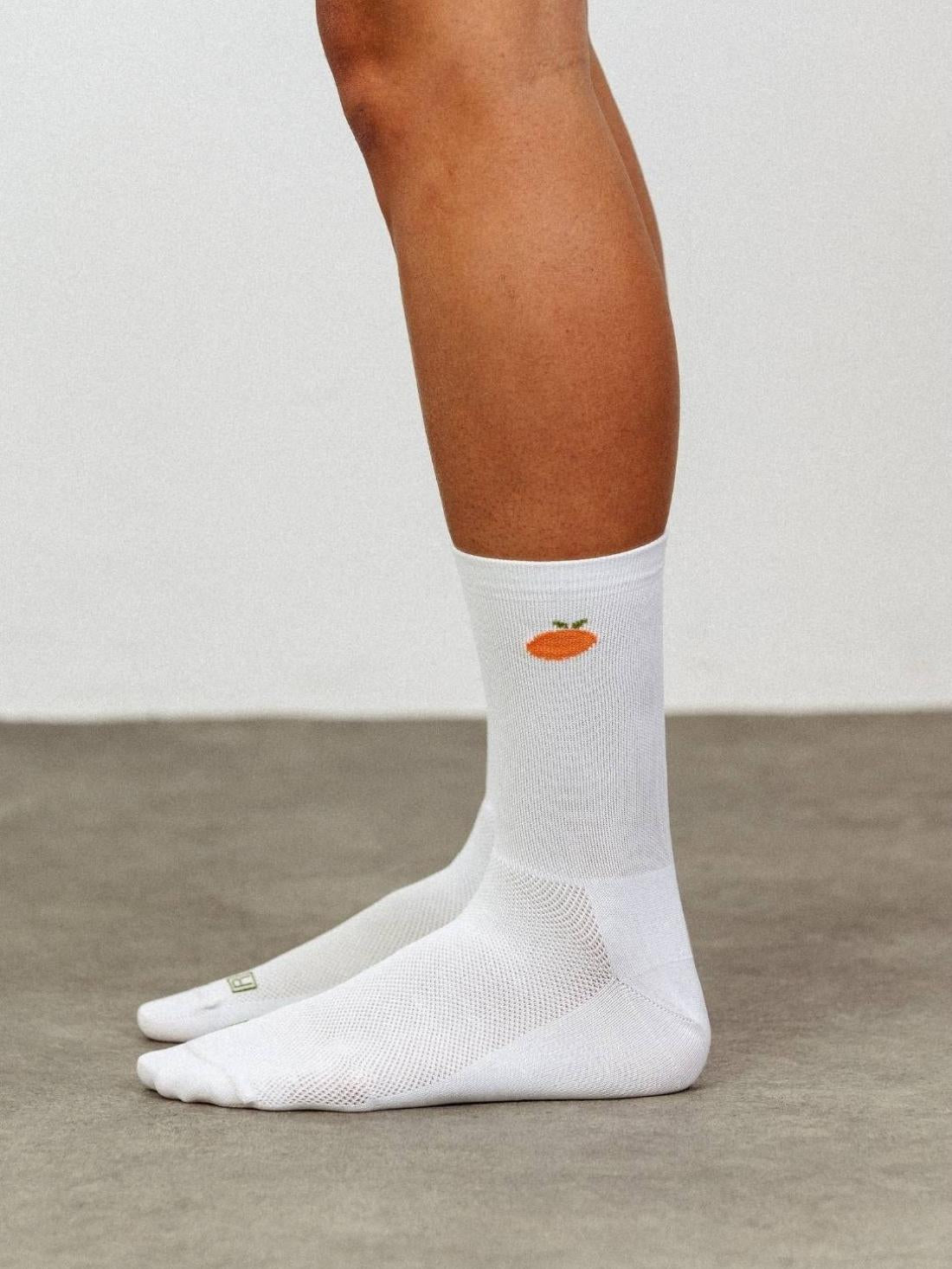 On-leg side view of white POP Cycling Co. Fruity Socks showing secure compressive fit for road cycling.