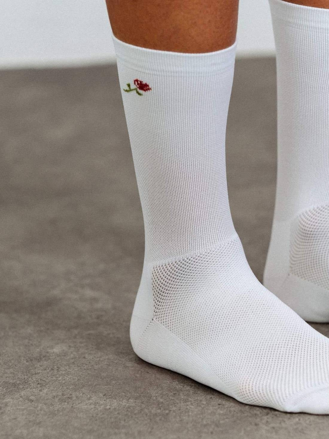 Close-up detail of white Q-Skin polyamide fabric with embroidered-style rose logo and breathable mesh.