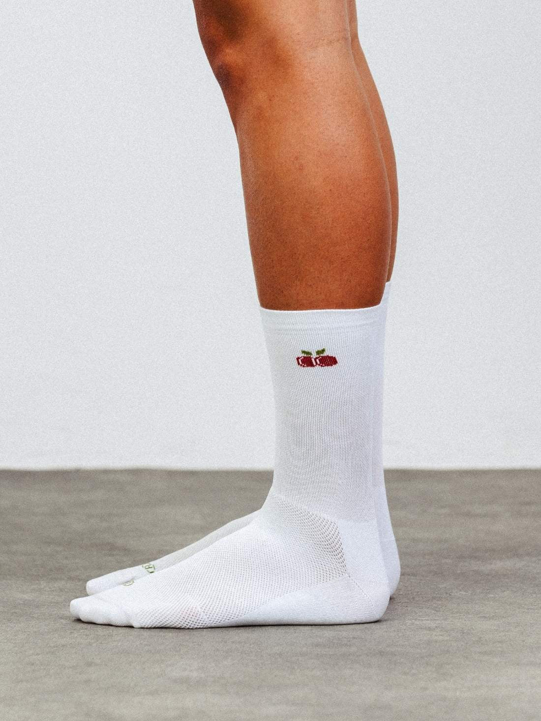 Side profile of white cycling socks featuring a red cherry fruit pattern and high compression fit.