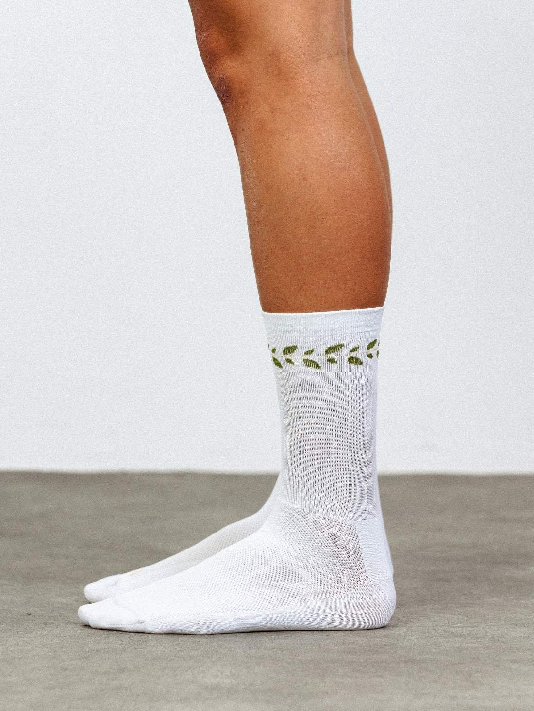 Side profile of white cycling socks featuring a classic laurel leaf pattern and high compression fit.