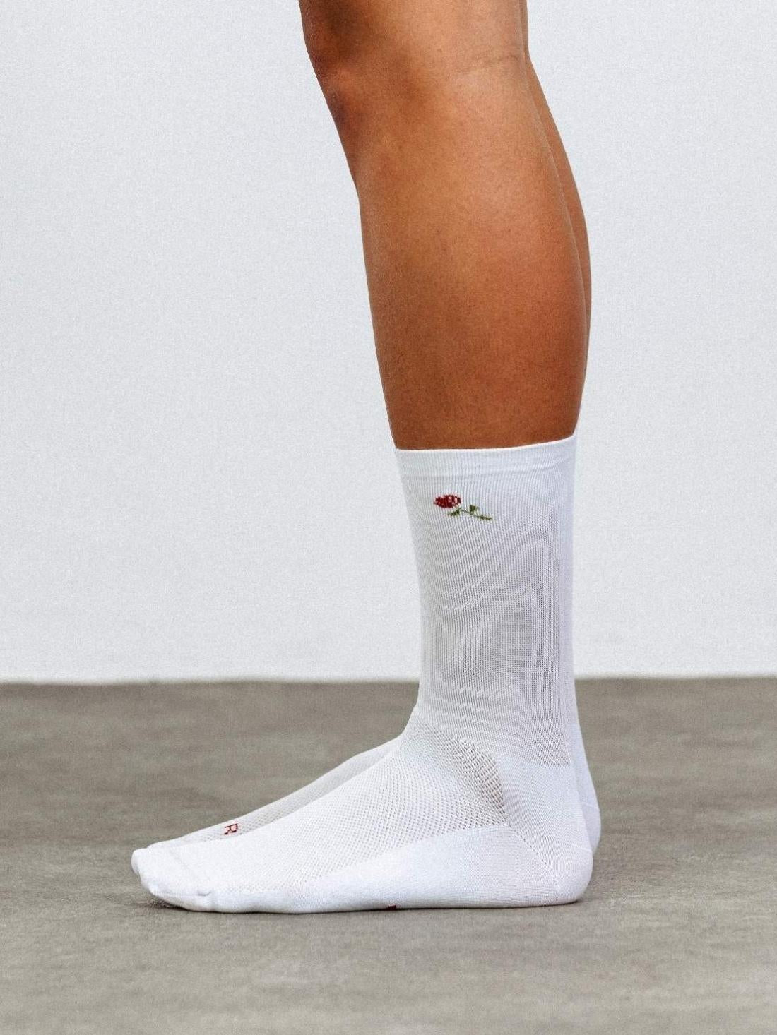 Side profile of white high compression cycling socks featuring a red rose flower design and 18cm cuff.
